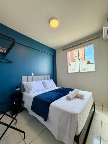a blue bedroom with a bed with two towels on it at Apto com 2 quartos e A/C no Centro e Santa Casa in Montes Claros