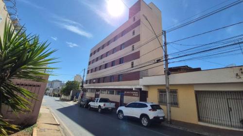 two white cars parked in front of a building at Apto com 2 quartos e A/C ao lado da Santa Casa in Montes Claros