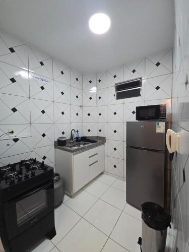 a kitchen with a black and white tiled wall at Apto com 2 quartos e A/C no Centro in Montes Claros