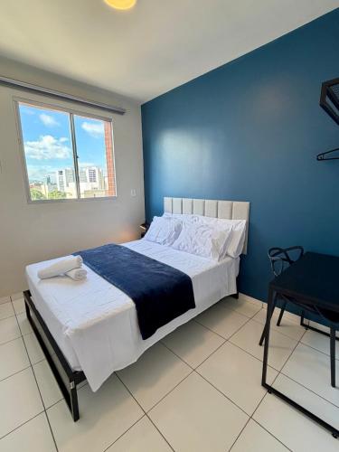 a bedroom with a large bed with a blue wall at Apto com 2 quartos e A/C no Centro in Montes Claros