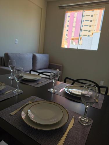 a table with plates and wine glasses on it at Apto com 2 quartos e A/C no Centro in Montes Claros