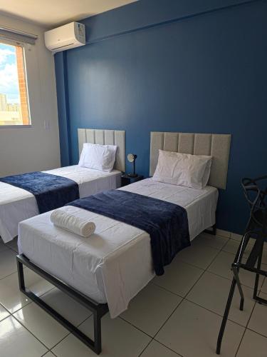 two beds in a room with blue walls at Apto com 2 quartos e A/C no Centro in Montes Claros