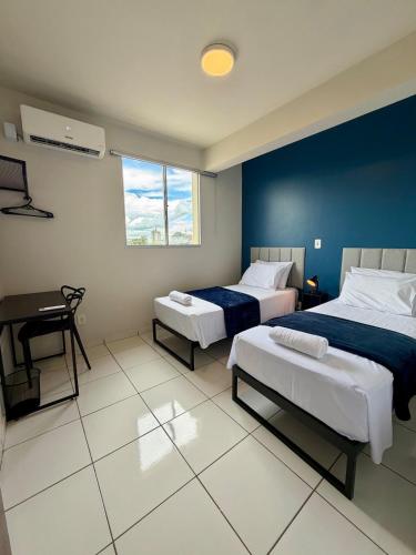 a bedroom with two beds and a desk in it at Apto com 2 quartos e A/C no Centro in Montes Claros