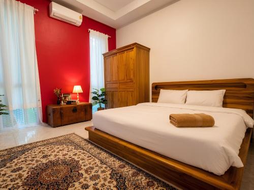 a bedroom with a large bed and a red wall at Villa Monroe - Elegant Private Pool Villa in Ban Nok