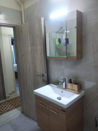a bathroom with a sink and a wooden door at Proche CENTRE VILLE - BALCON - VUE - Calme in Igoumenitsa