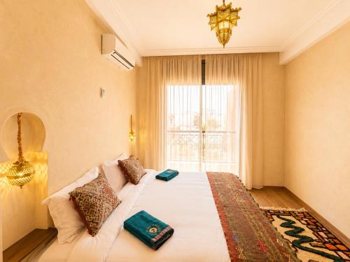 a bedroom with a bed with a chandelier and a window at Wave chaser surfhouse morocco in Agadir