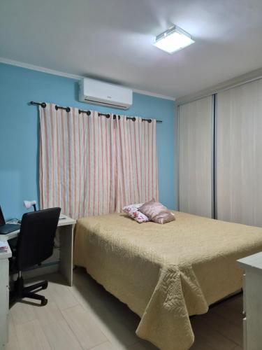 a bedroom with a bed and a desk and a chair at orquídea in Paulínia