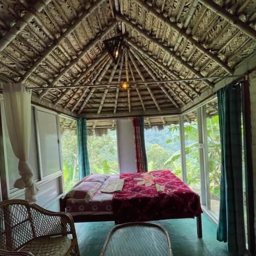 a bedroom with a bed in a room with windows at The Cloud door in Perumālmalai