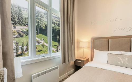 a bedroom with a bed and a large window at Hotel Montfort in Nicolet