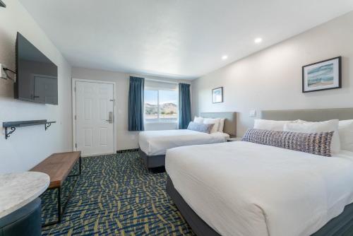 a hotel room with two beds and a table at The Grove at Pismo Beach in Pismo Beach