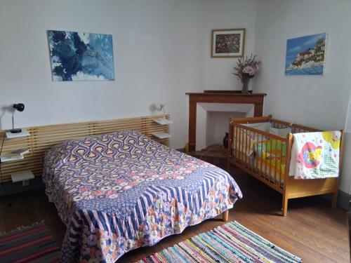 a bedroom with a bed and a crib in it at La maison du Thoré in Saint-Amans-Valtoret