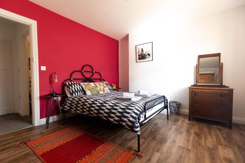 a bedroom with a bed and a red wall at JACKS COTTAGE - Cosy Cottage in the Heart of Richmond in Richmond