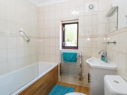 a bathroom with a tub and a toilet and a sink at Lowbrook Cottage in Diss