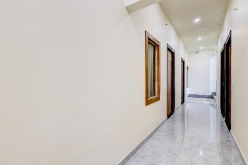 a hallway with white walls and paintings on the walls at Hotel O DREAM INN in Alwar