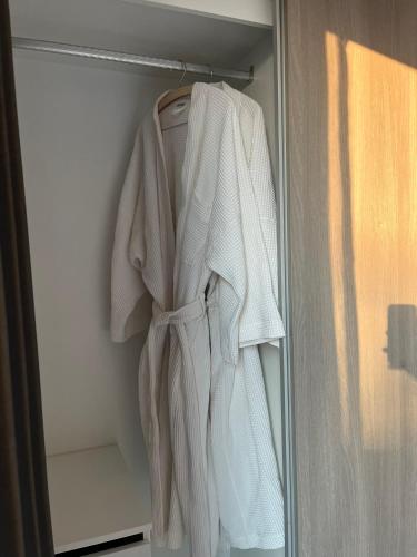 a white robe is hanging in a refrigerator at Mega Bangna Studio Retreat in Bang Kew Yai