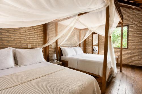 a bedroom with two beds and a canopy at Casa Fufi in Jericoacoara