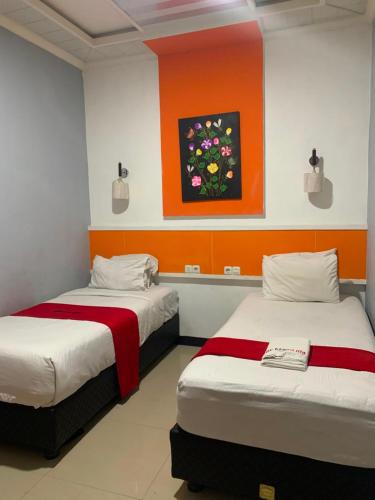 two beds in a room with a painting on the wall at Hy ReDz in Palopo
