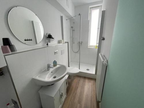 ein weißes Badezimmer mit Waschbecken und Spiegel in der Unterkunft Brigg in Emden