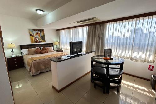 a bedroom with a bed and a desk with a television at Suites Jardín Imperial in Guatemala