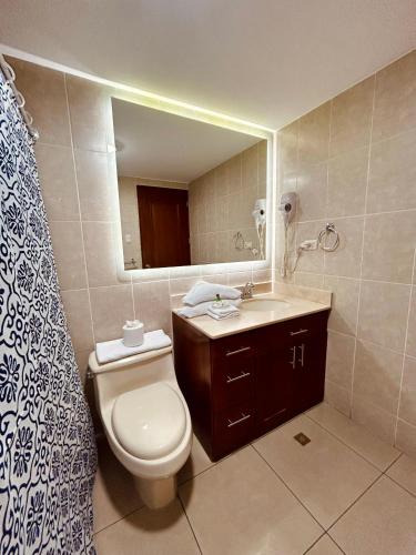 a bathroom with a toilet and a sink and a mirror at Suites Jardín Imperial in Guatemala