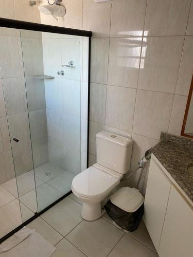 a bathroom with a toilet and a glass shower at Serra Negra Pousada Spa - by Easy Hotéis in Guarapari