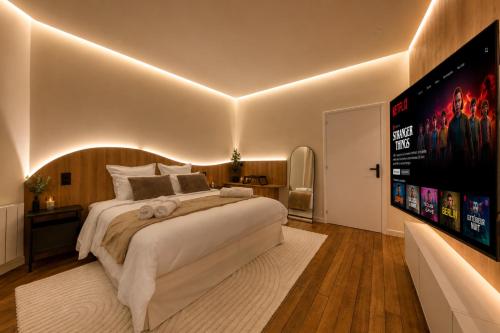a bedroom with a large bed and a large screen at Suite Prestige Spa Privatif D'exception in LʼIsle-Adam