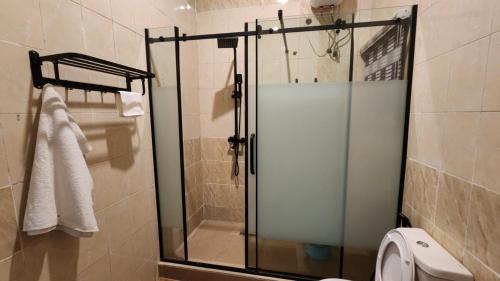 a bathroom with a shower with a toilet and a glass door at LaCasa Abuja in Abuja