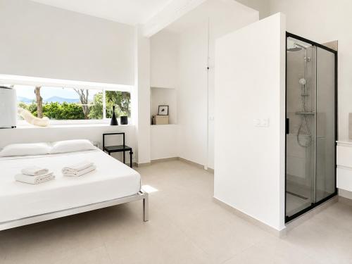 a white bedroom with a bed and a shower at ÉLÉGANT STUDIO et PARKING DANS BATIMENT HISTORIQUE in Saint-Tropez