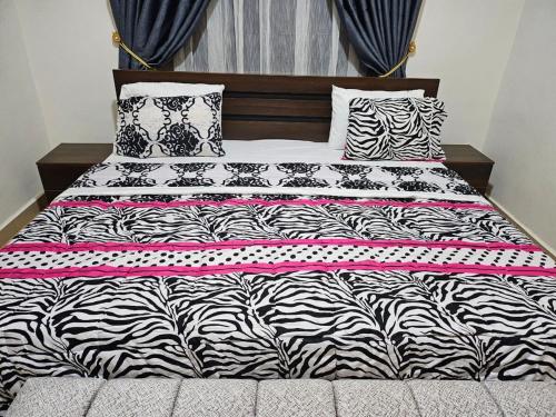 a bed with a black and white comforter and pillows at LaCasa Abuja in Abuja