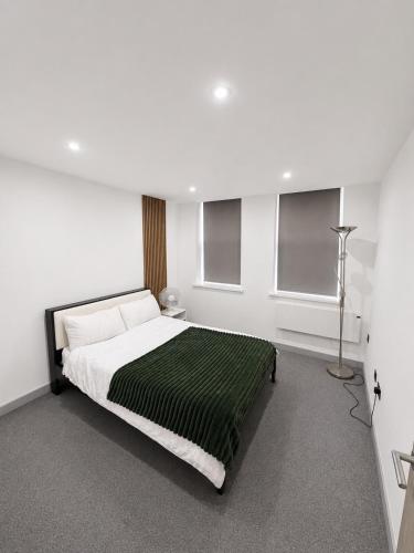 a white bedroom with a bed with a green blanket at AS Residences in Preston