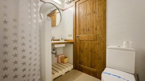 a bathroom with a toilet and a wooden door at Chez Bonheur in Osséja