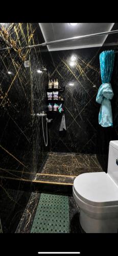 a bathroom with a toilet and a black tiled wall at Mezbon in Termiz