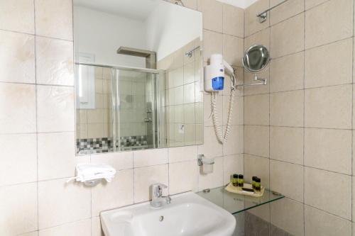 a white bathroom with a sink and a mirror at Maria's Place - Adults Only in Oia