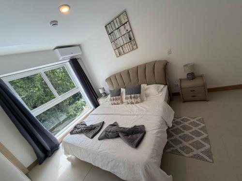 a bedroom with a large bed with two clothes on it at livejaco405A in Jacó