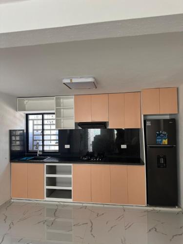 a kitchen with brown cabinets and a black refrigerator at Carrasco D in Nagua