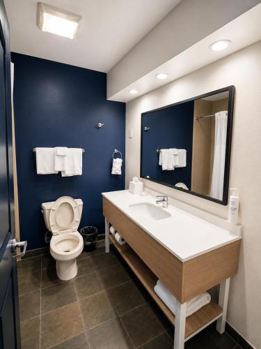 a bathroom with a toilet and a sink and a mirror at Spark By Hilton Lake George Outlets in Lake George
