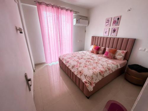 a bedroom with a large bed with pink curtains at Cinema Experience -Premium Studio in Karnal