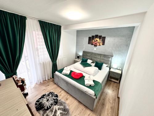 a bedroom with a large bed with green curtains at Cabana Mea STRAJA in Lupeni