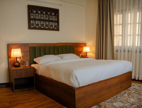 a bedroom with a large bed with white sheets and pillows at Gakyi Homes Boudha in Kathmandu