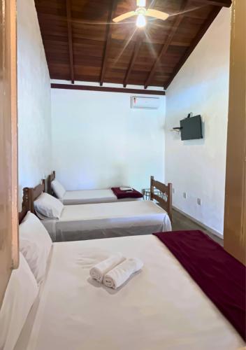 a room with two beds and a ceiling fan at Chalés Terra Santa Capitólio in Capitólio
