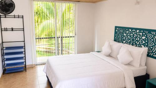 a bedroom with a white bed and a large window at HOTEL NATIVOS in La Vega