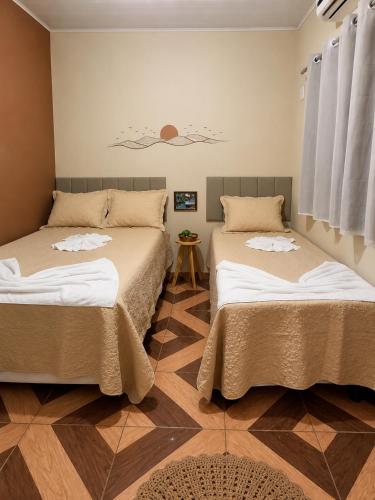 a room with two beds and a table at Sol do Jalapão Kitnets Completas com Ar a 6km do Aeroporto de Palmas in Palmas