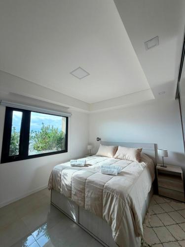 a white bedroom with a large bed and a window at Edificio Guay I in Concepción del Uruguay