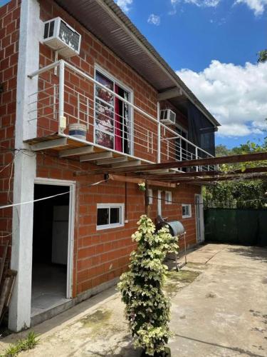 a brick house with a balcony and a plant at Cabañas Sagrado Corazón in Ituzaingó