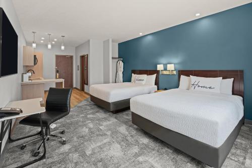 a hotel room with two beds and a desk at Home Inn & Suites Regina Airport in Regina