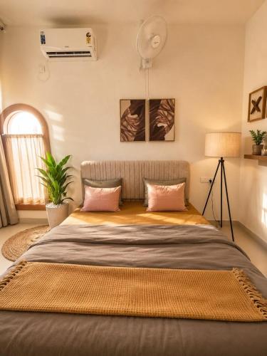 a bedroom with a large bed with pink pillows at Luxurious boho pool villa nandi hills in Bangalore