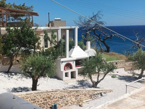 a white house with a stove in front of the ocean at Aigialos Villas with Private Beach by Hospi Living in Ferma