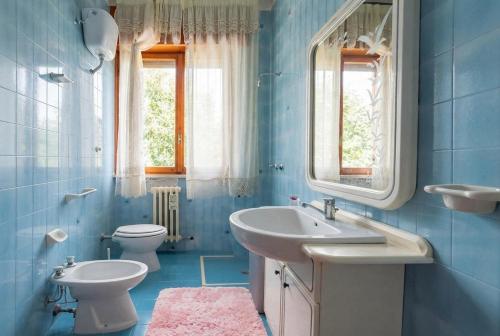 a blue bathroom with two sinks and a toilet at Dimora Giovanna in Poggiardo