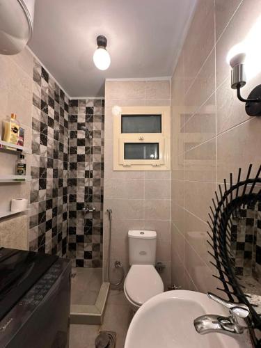 a bathroom with a toilet and a sink and a window at Agora resort north coast in Dawwār Abū Maḩrūs