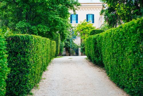 a path through a hedge with a building in the background at Agriturismo Castello Santa Margherita in Cori